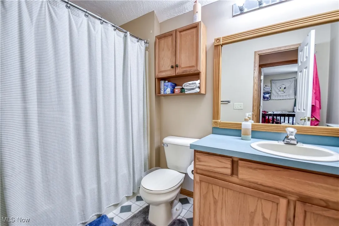 Full bath with tile patterned flooring, vanity, a textured ceiling, and a shower with curtain