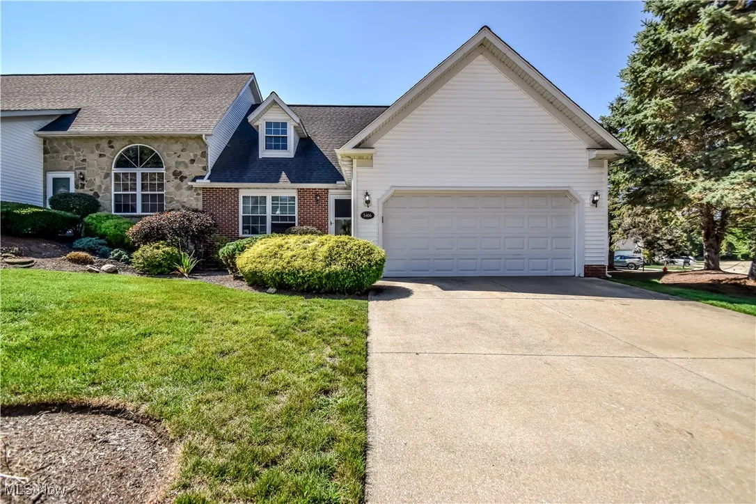 View of front of home with driveway, a front lawn, roof with shingles, and an attached garage