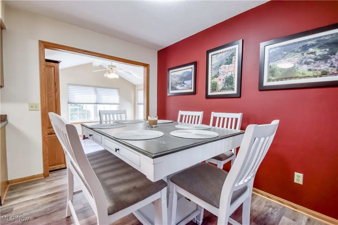 Dining area featuring light wood-style floors, vaulted ceiling, and a ceiling fan