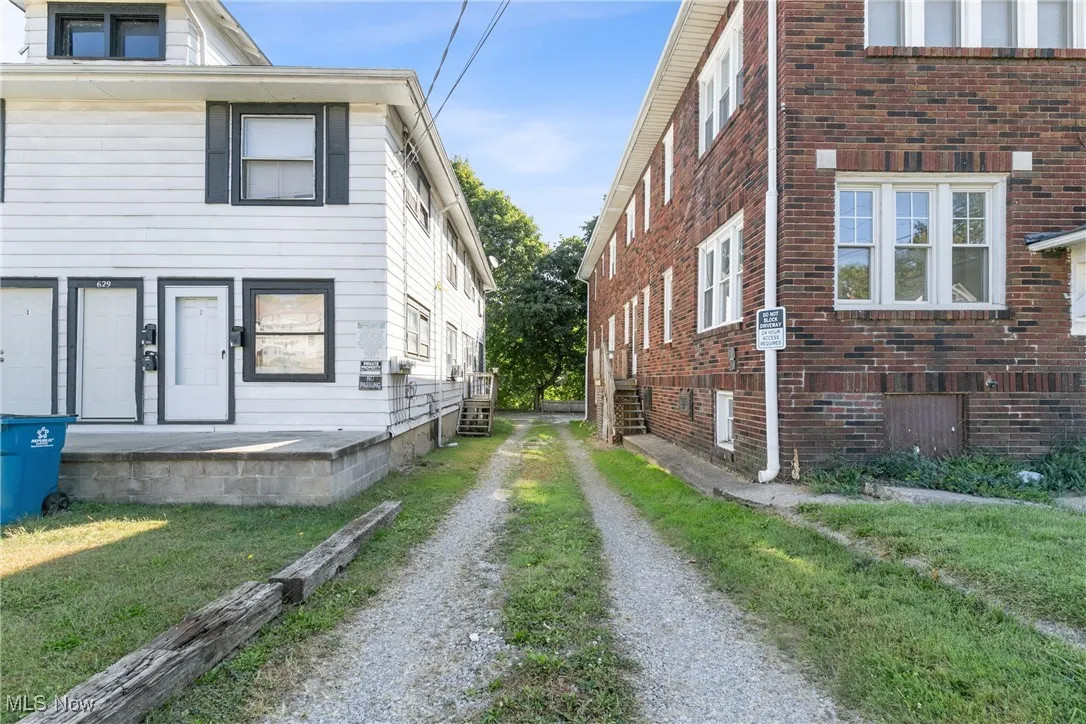 View of side of home featuring brick siding, driveway, and a lawn