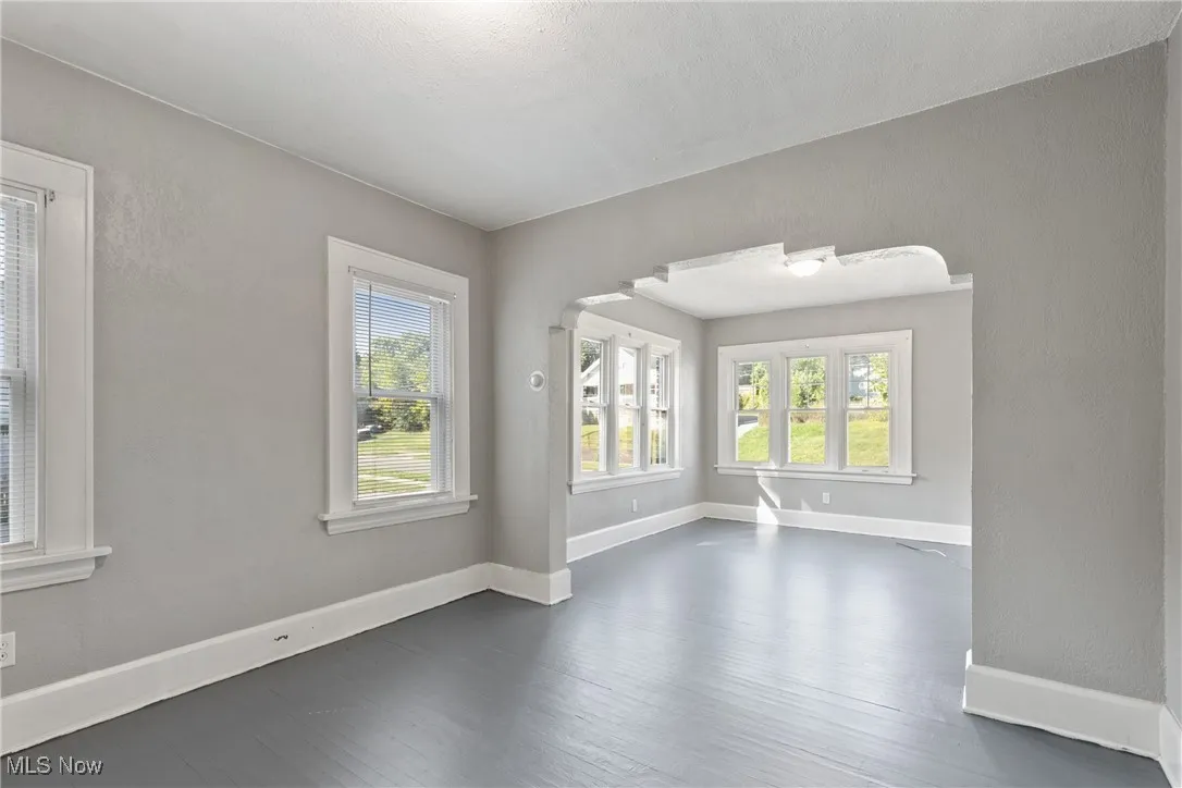 Unfurnished room with a textured wall, healthy amount of natural light, and dark wood-style floors