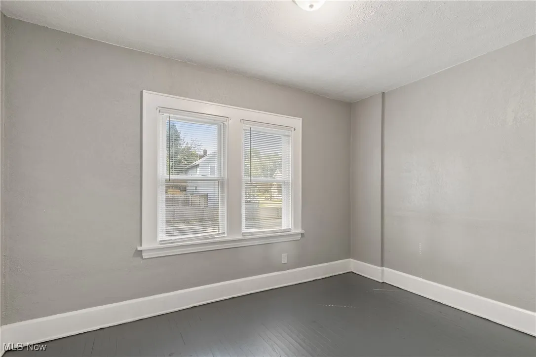 Unfurnished room featuring dark wood-style flooring and a textured wall