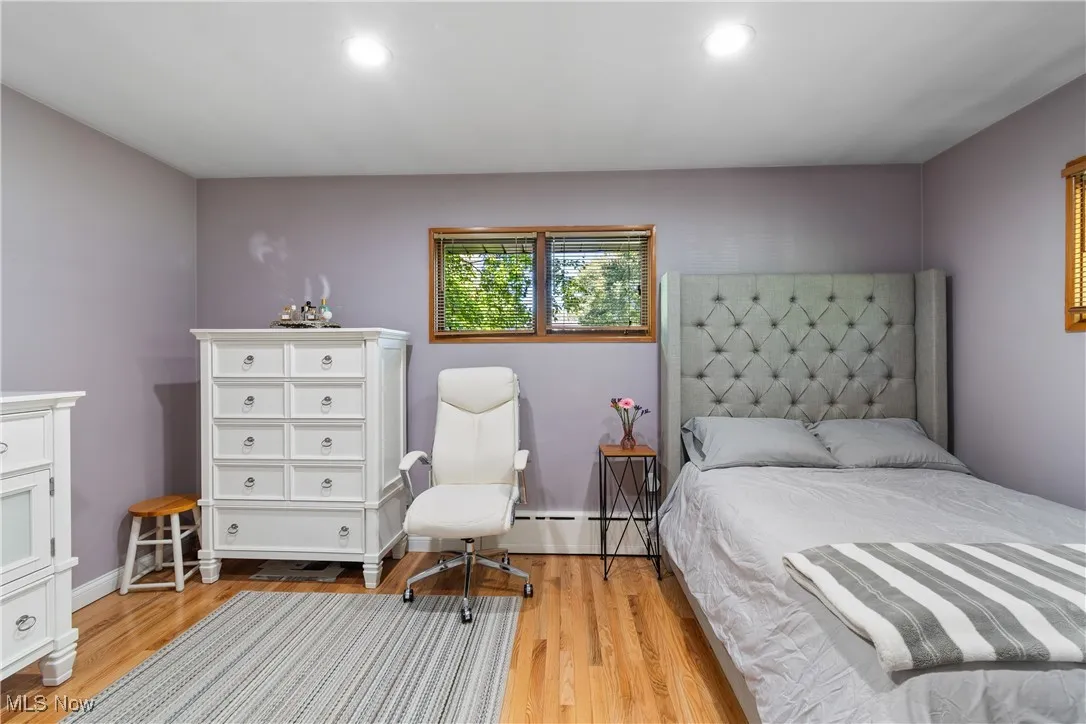 Bedroom featuring light wood-type flooring, a baseboard heating unit, and recessed lighting