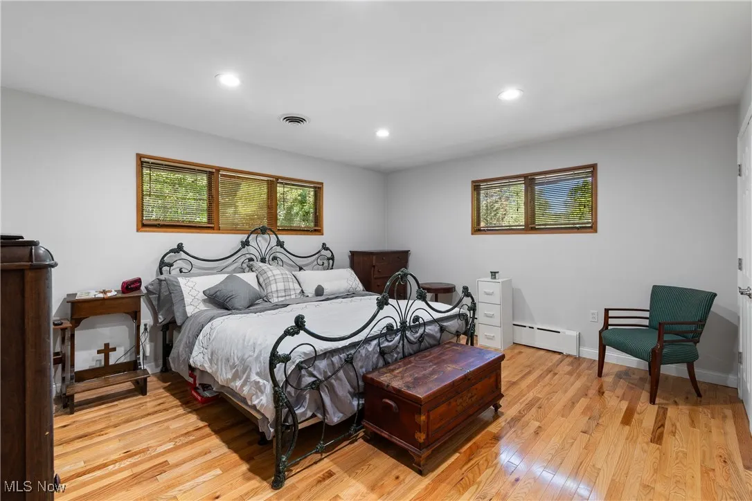 Bedroom featuring light wood-type flooring, recessed lighting, and a baseboard radiator