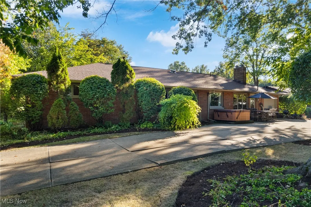 Ranch-style home with a hot tub, brick siding, a chimney, and roof with shingles