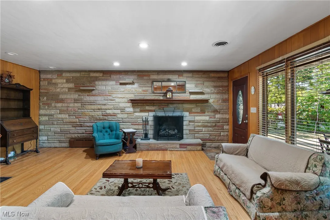 Living room with wood walls, recessed lighting, a fireplace, and wood finished floors