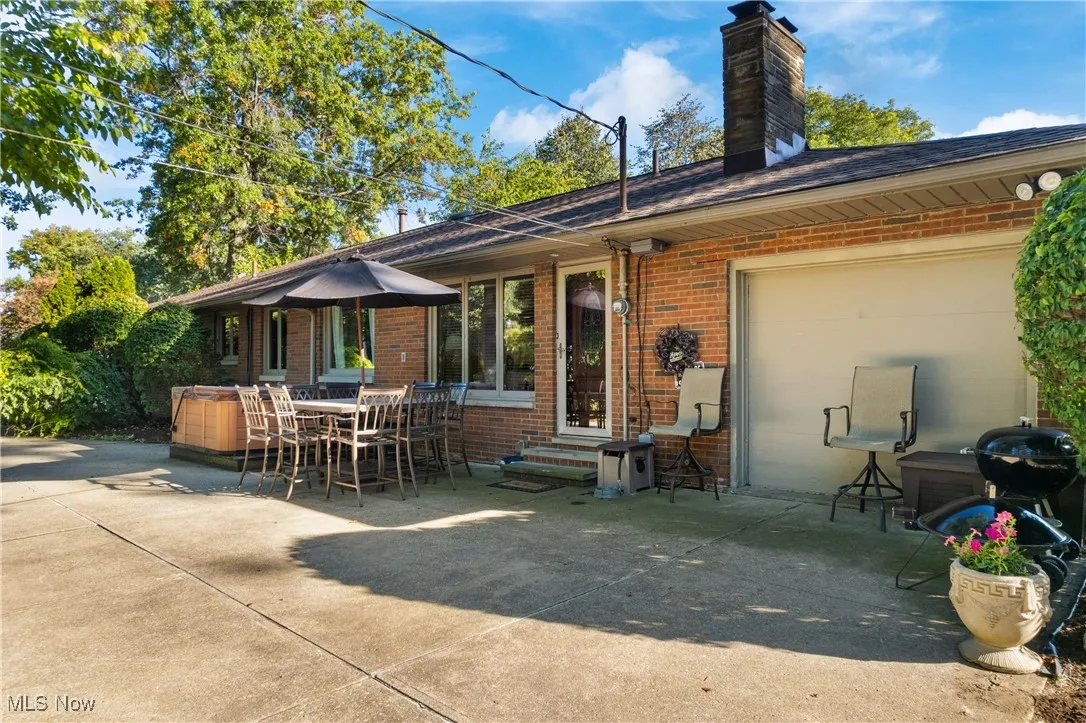 Rear view of property with brick siding, a patio area, and a chimney