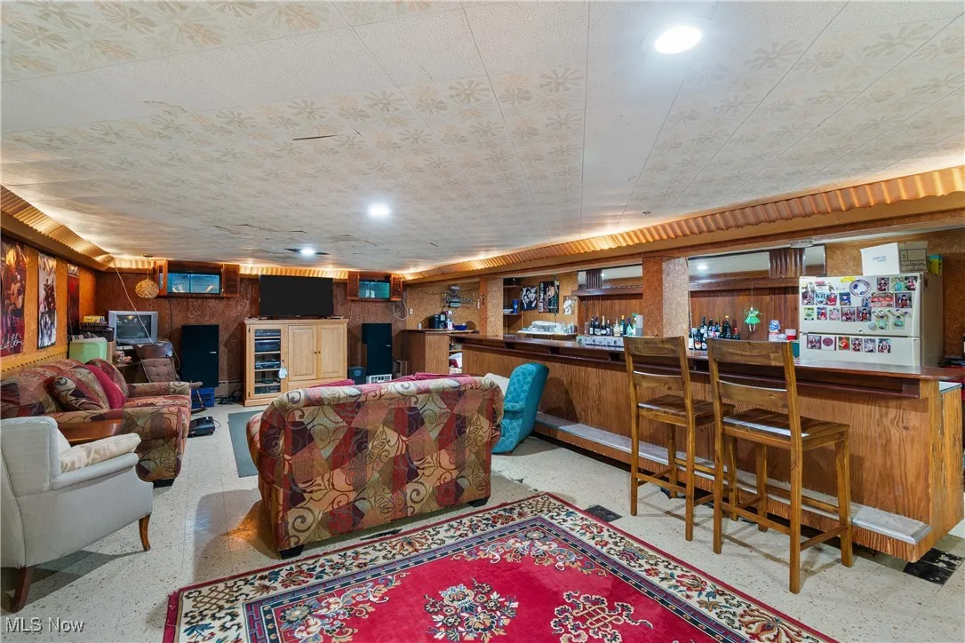 Living room featuring a dry bar, wood walls, speckle patterned floor, and recessed lighting