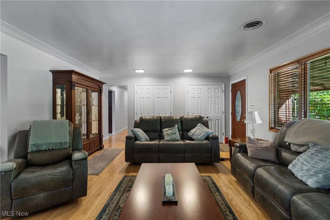Living area featuring wood finished floors and crown molding