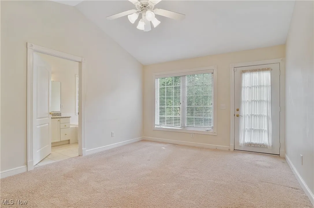 lofted ceiling, ceiling fan, ensuite bath, and access to exterior deck