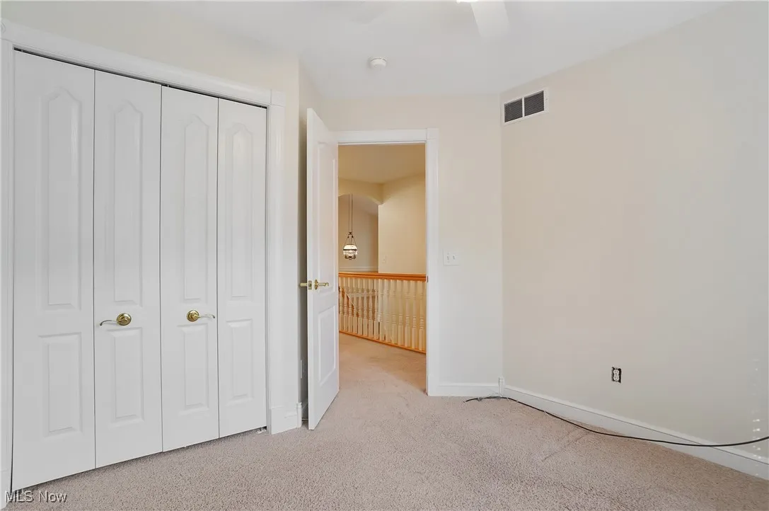 2nd bedroom with light colored carpet, closet, and ceiling fan