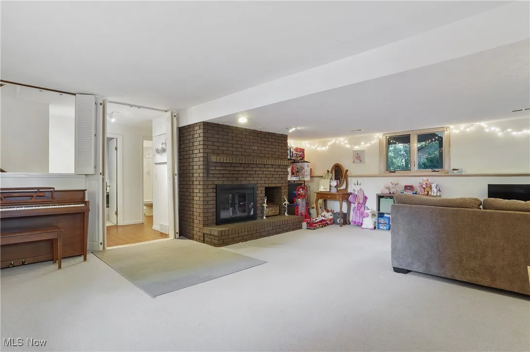 Living area with light carpet and a brick fireplace
