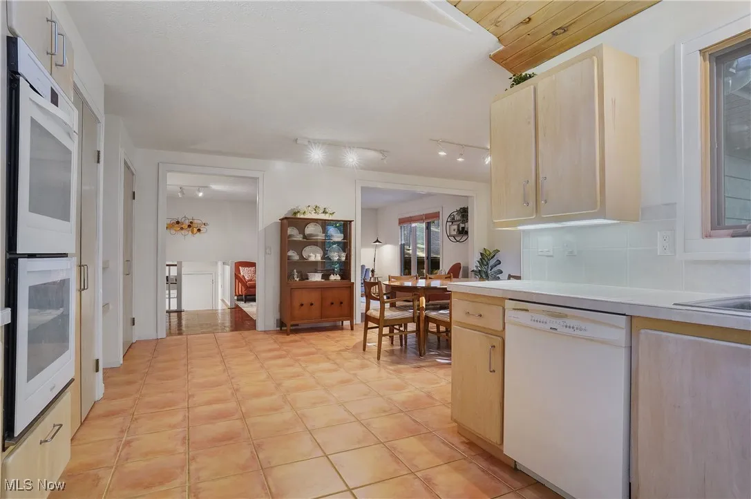 Kitchen with light brown cabinetry, white appliances, and light countertops