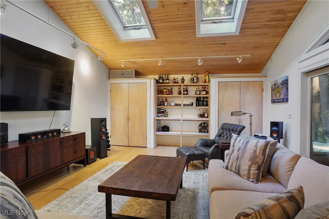 Living area featuring wood ceiling, light wood finished floors, lofted ceiling, and a skylight