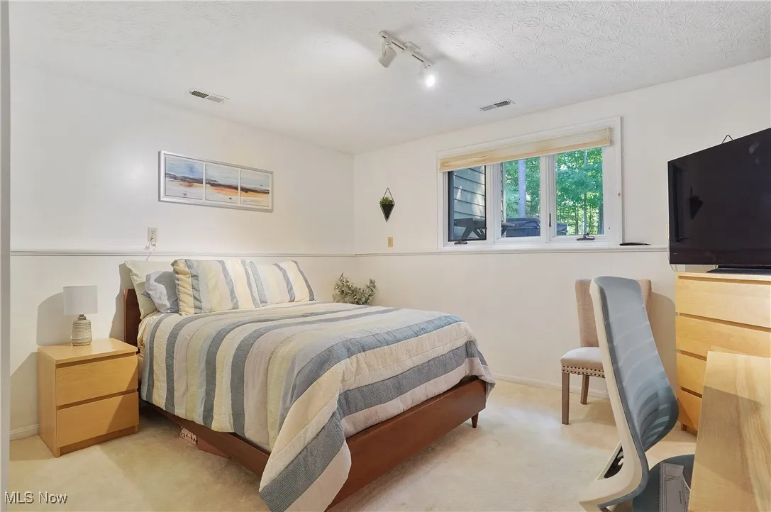 Carpeted bedroom featuring rail lighting and a textured ceiling