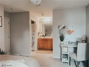 Bedroom featuring light carpet and connected bathroom