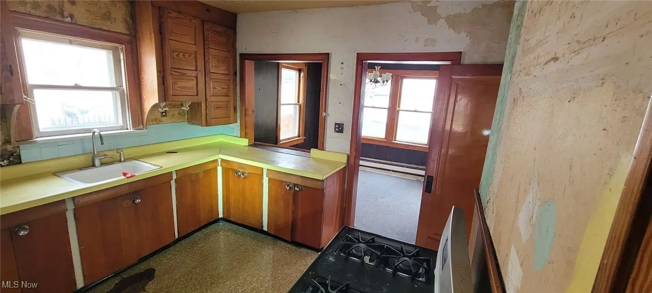 Kitchen with light countertops, brown cabinets, a baseboard radiator, and dark flooring