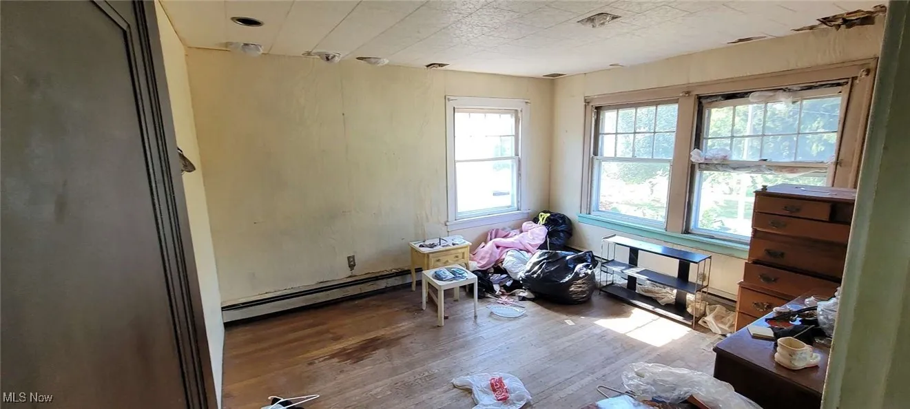 Unfurnished room featuring wood finished floors and baseboard heating
