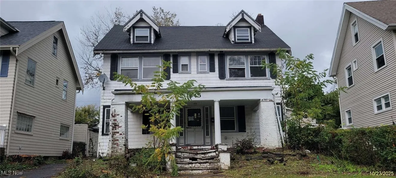 View of front facade with a chimney, covered porch, and roof with shingles