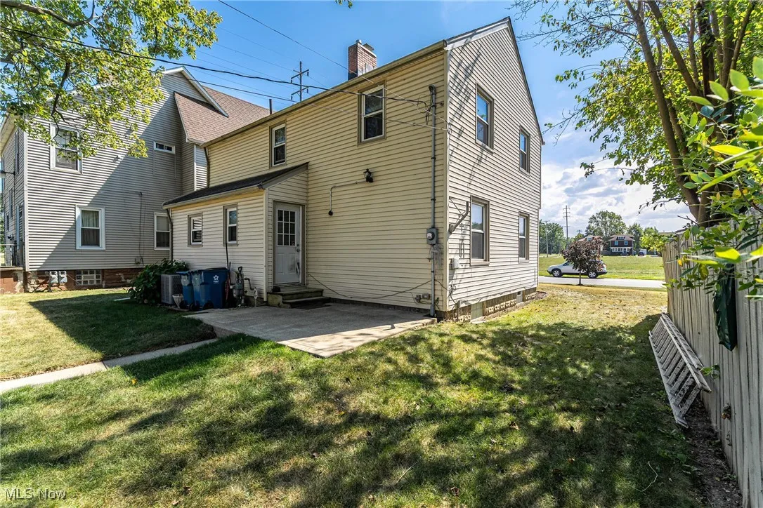 Rear view of house with a patio area, a chimney, and a yard
