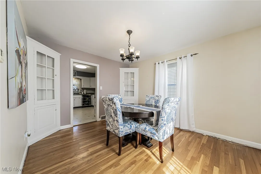 Dining area with light wood finished floors, a chandelier, and beverage cooler