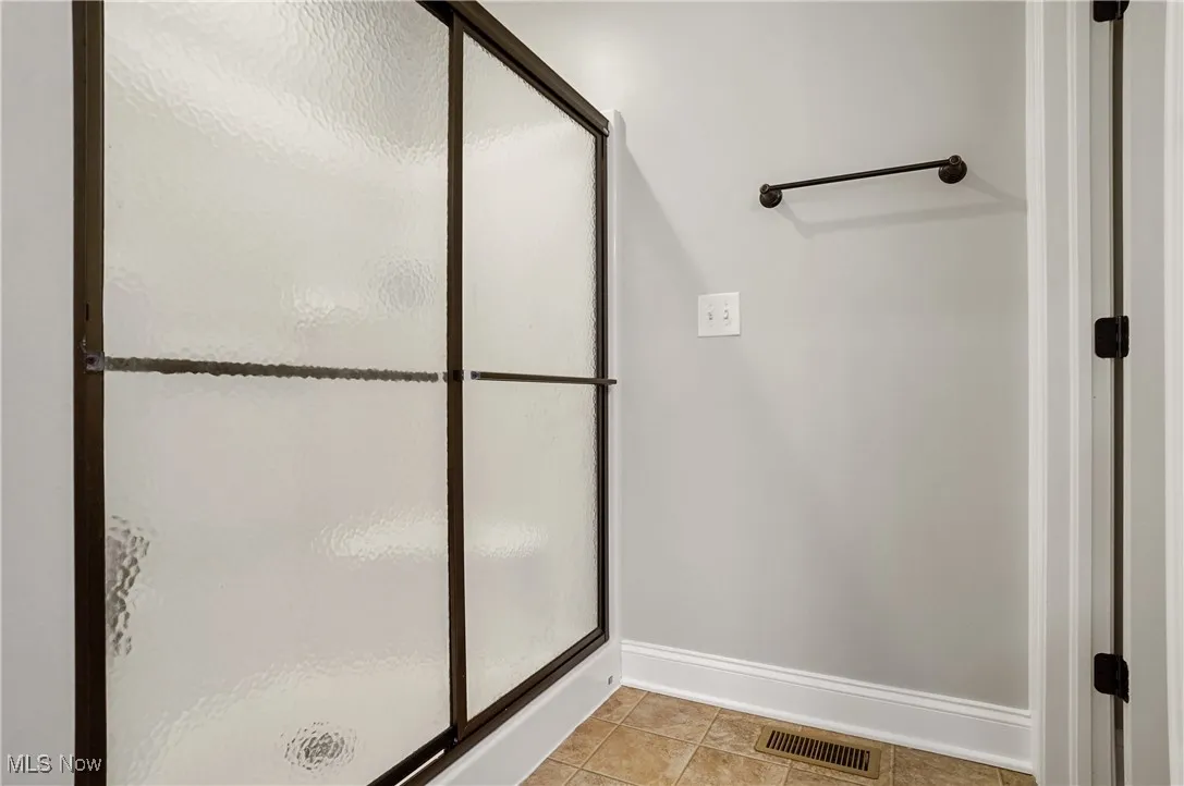 Bathroom with a shower stall and light tile patterned floors