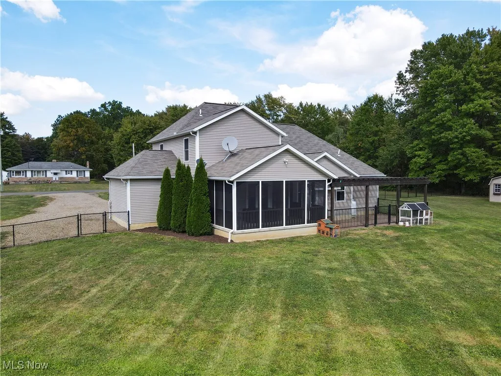 Rear view of property featuring a sunroom and roof with shingles