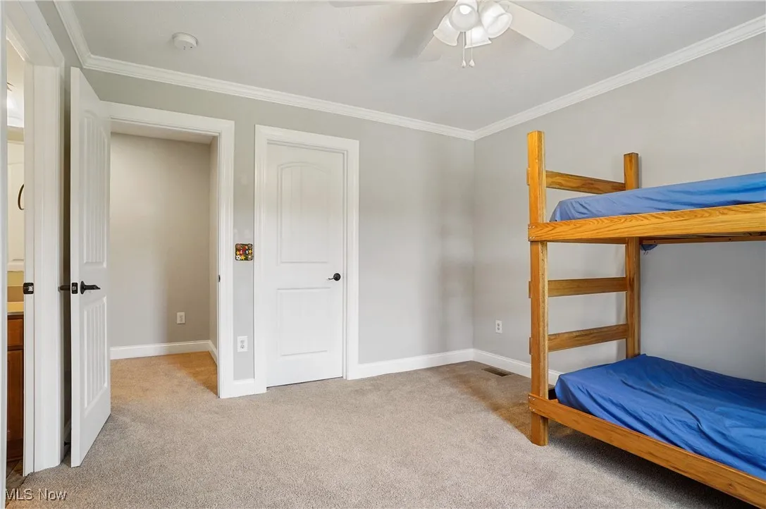 Bedroom with ornamental molding, light colored carpet, and a ceiling fan
