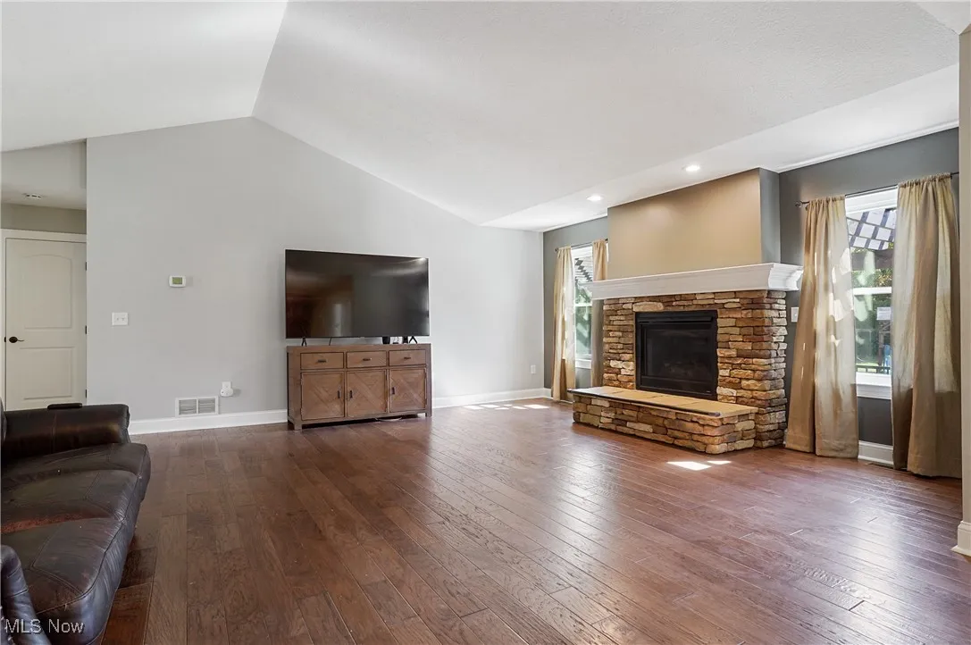 Living area featuring healthy amount of natural light, lofted ceiling, hardwood / wood-style floors, a fireplace, and recessed lighting