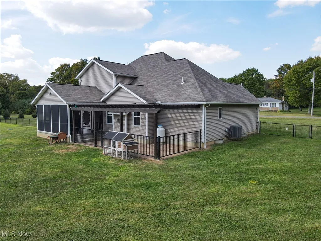 Rear view of property featuring roof with shingles and a sunroom