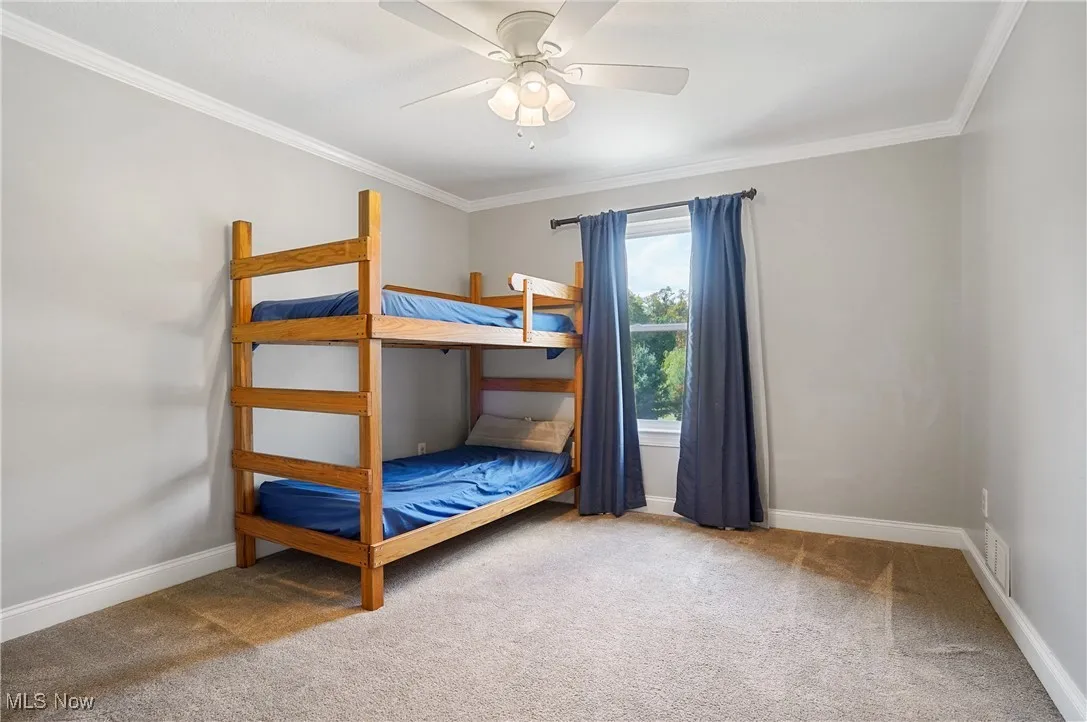 Bedroom featuring crown molding, light colored carpet, and a ceiling fan