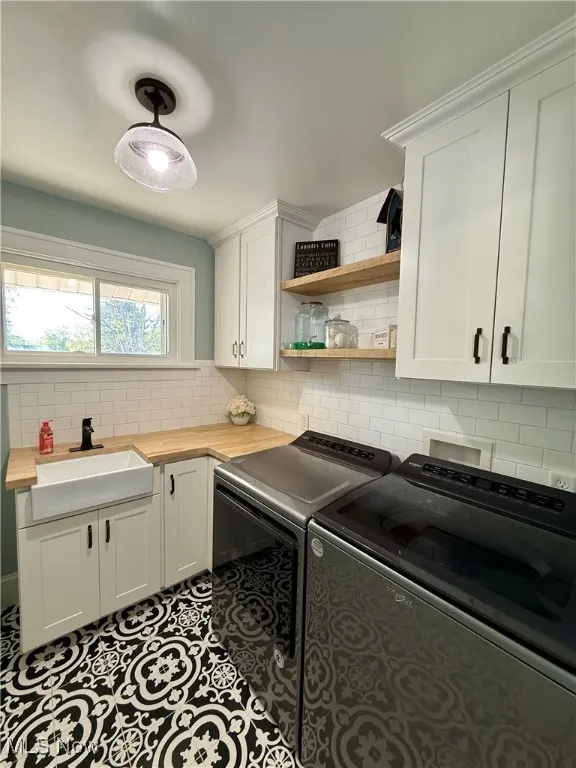 Washroom featuring cabinet space, washing machine and clothes dryer, and tile patterned floors