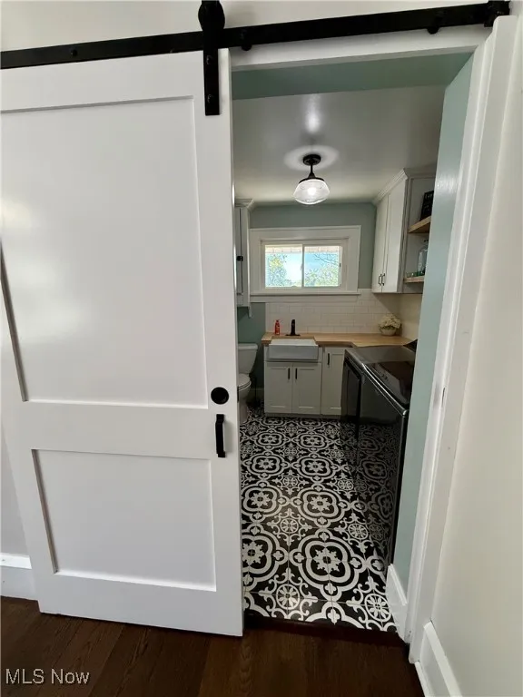 Laundry area with a barn door and dark wood-style floors