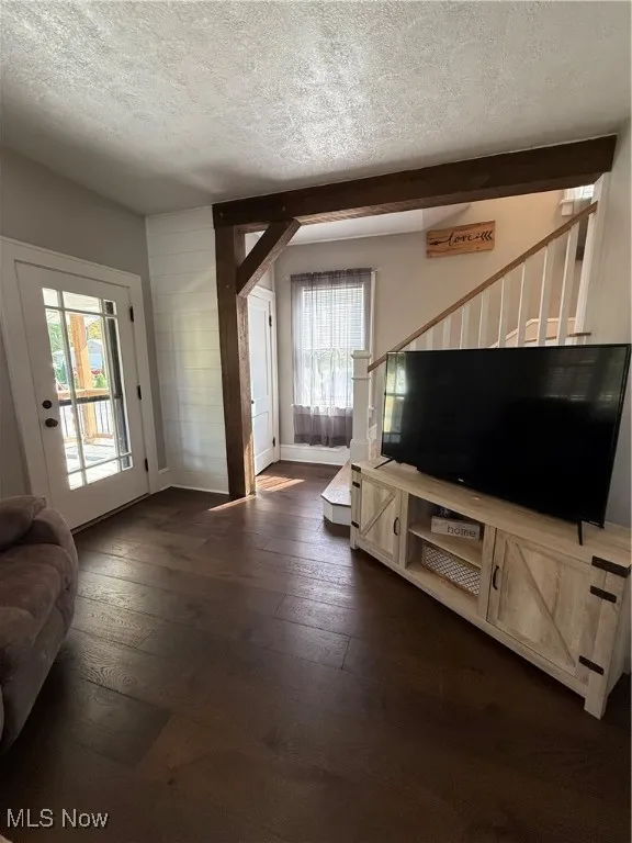 Living area featuring a textured ceiling, stairs, and dark wood-style floors