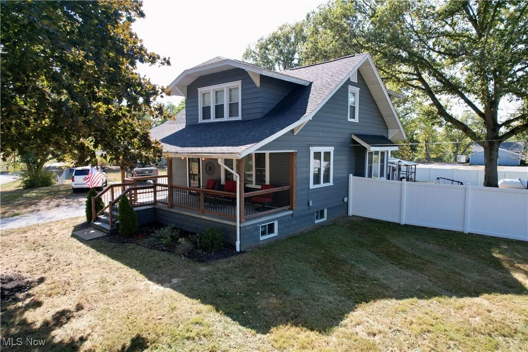Back of property featuring a shingled roof and a wooden deck
