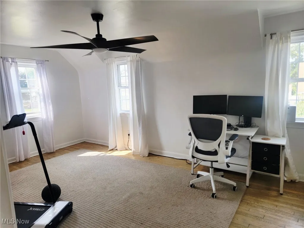Home office with light wood-type flooring, healthy amount of natural light, and a ceiling fan