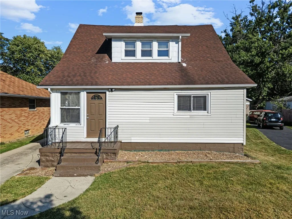 View of front of house featuring a front lawn, a chimney, and roof with shingles