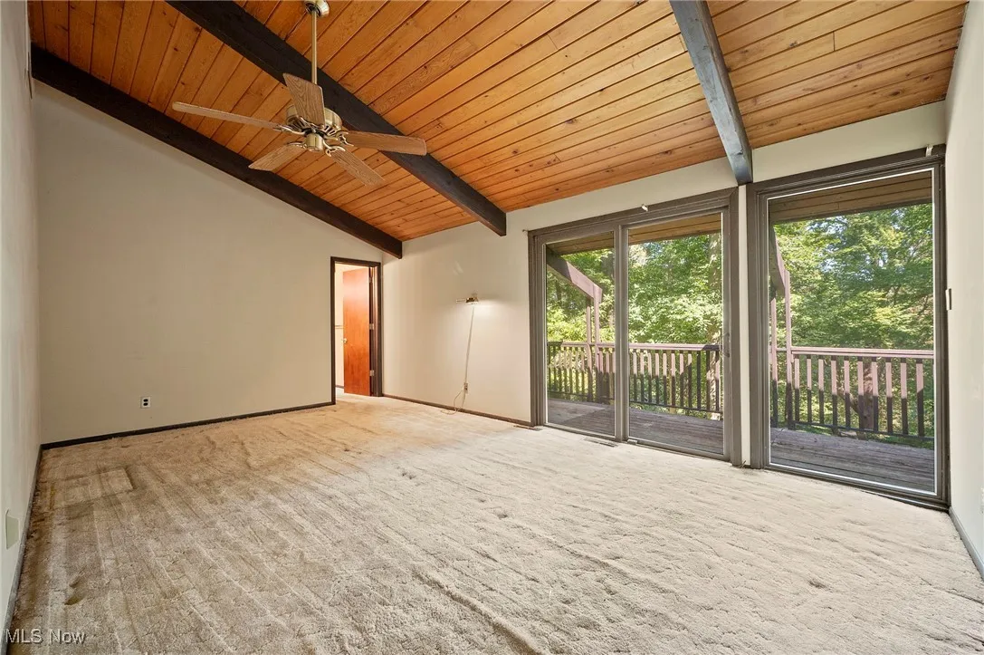 Unfurnished living room featuring wood ceiling, carpet flooring, and a ceiling fan