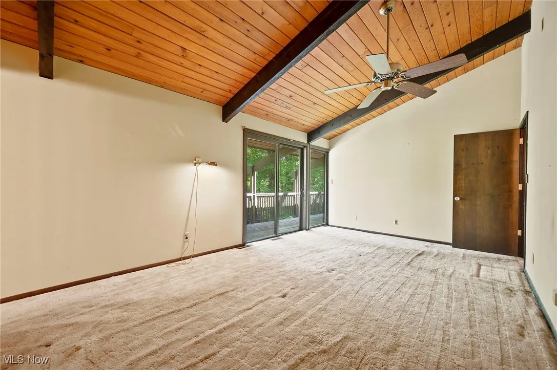Carpeted spare room featuring a wooden ceiling with exposed beams, high vaulted ceiling, and a ceiling fan