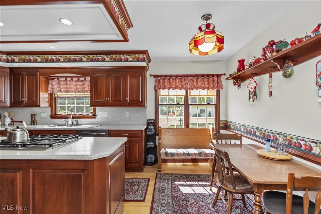 Kitchen with light wood-type flooring, tasteful backsplash, appliances with stainless steel finishes, light stone countertops, and open shelves