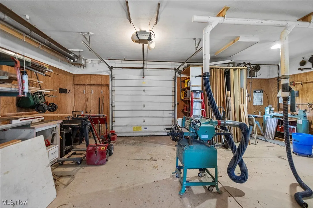 Garage featuring a workshop area, wooden walls, and a garage door opener