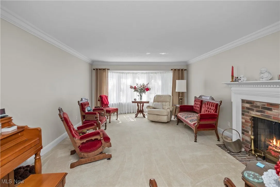 Carpeted living area featuring a brick fireplace and crown molding