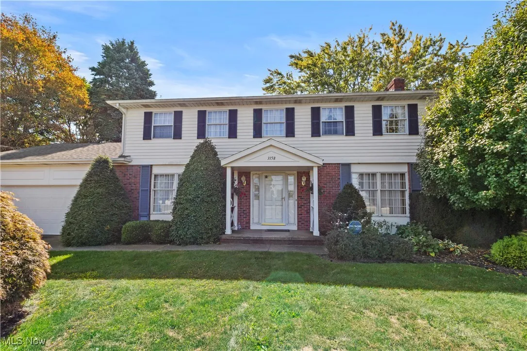 View of front of property with brick siding, a front yard, a chimney, and a garage
