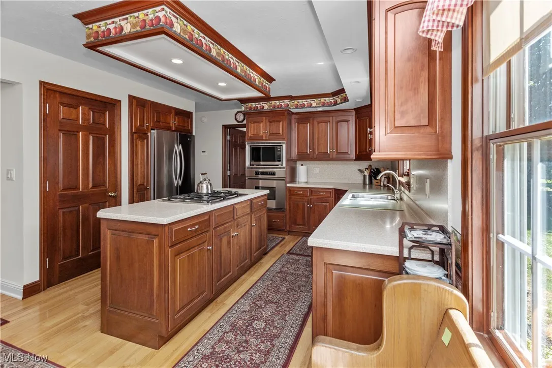 Kitchen featuring a center island, appliances with stainless steel finishes, recessed lighting, light wood-type flooring, and brown cabinets
