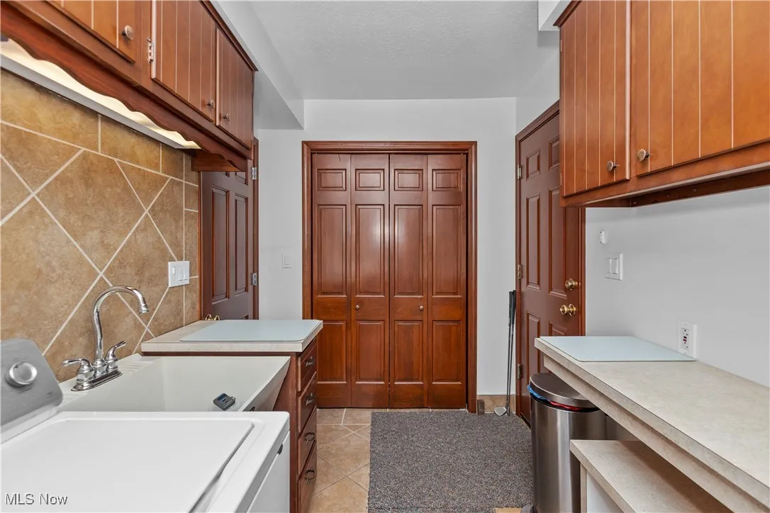 Washroom with washer / dryer, light tile patterned floors, cabinet space, and a textured ceiling