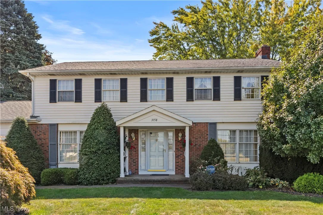 View of front of property with brick siding, a chimney, and a front yard