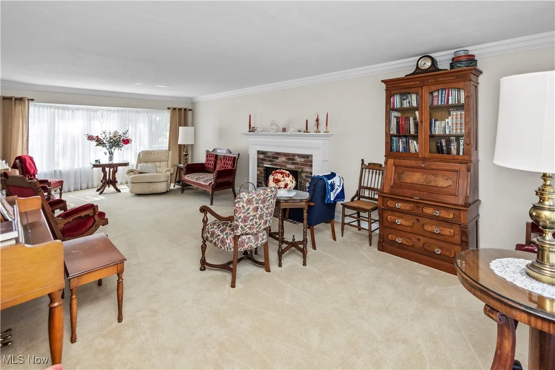 Living room with ornamental molding, a fireplace, and light colored carpet