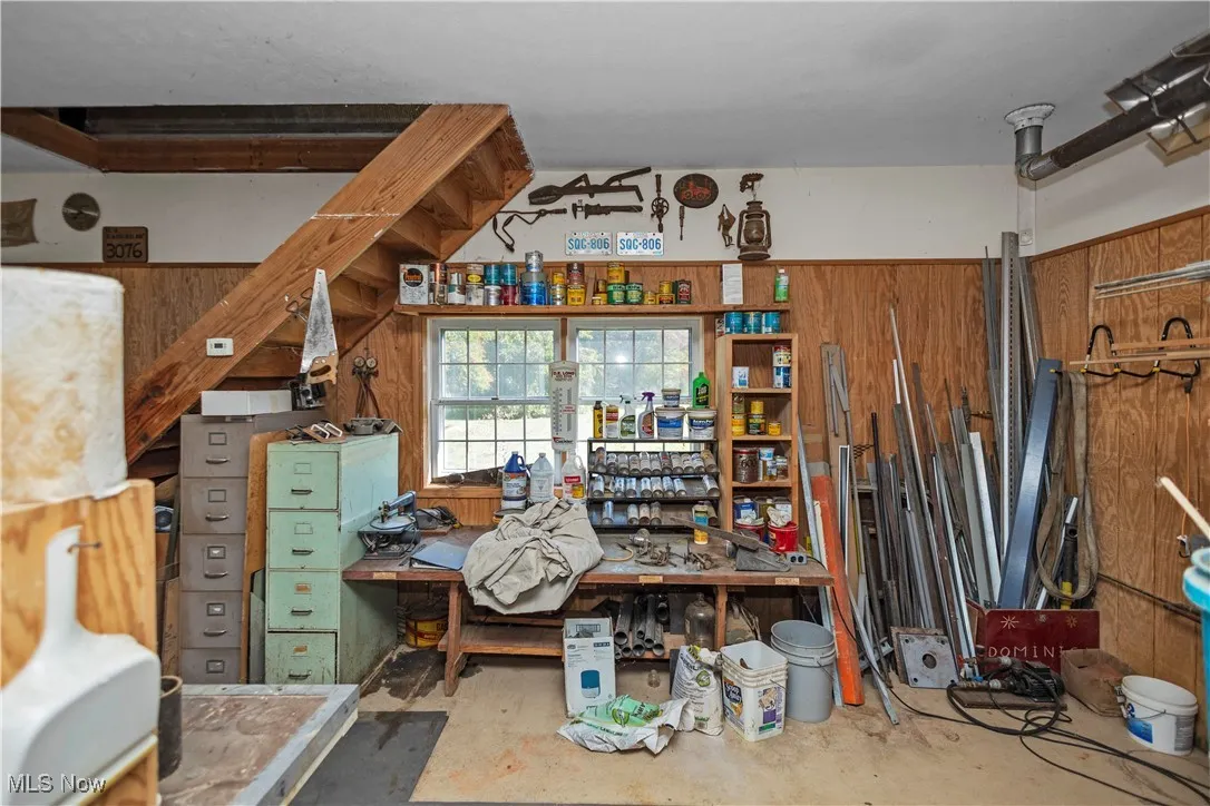 Misc room with concrete flooring, wood walls, and a workshop area