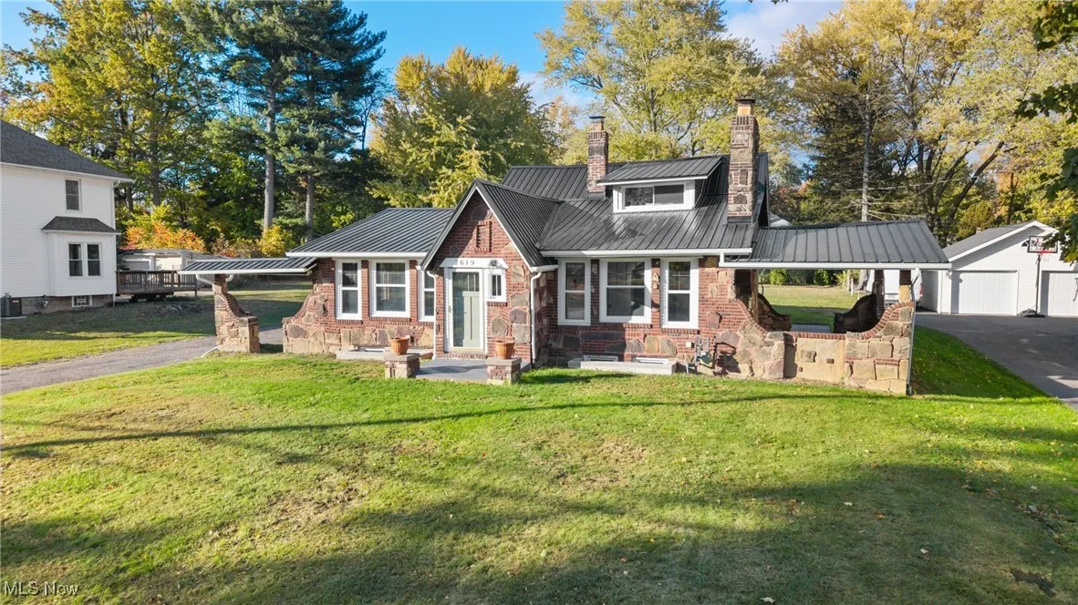View of front of home with a metal roof, a front yard, a chimney, a garage, and driveway