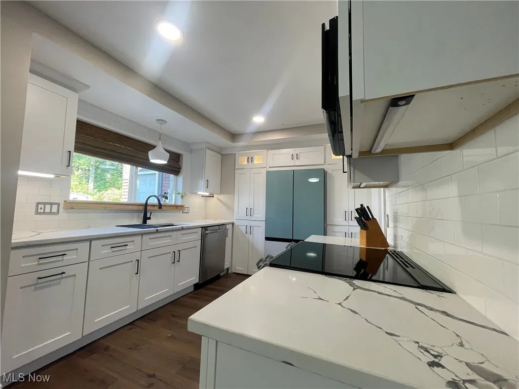Kitchen with decorative backsplash, white cabinetry, dark wood-style floors, light stone countertops, and recessed lighting
